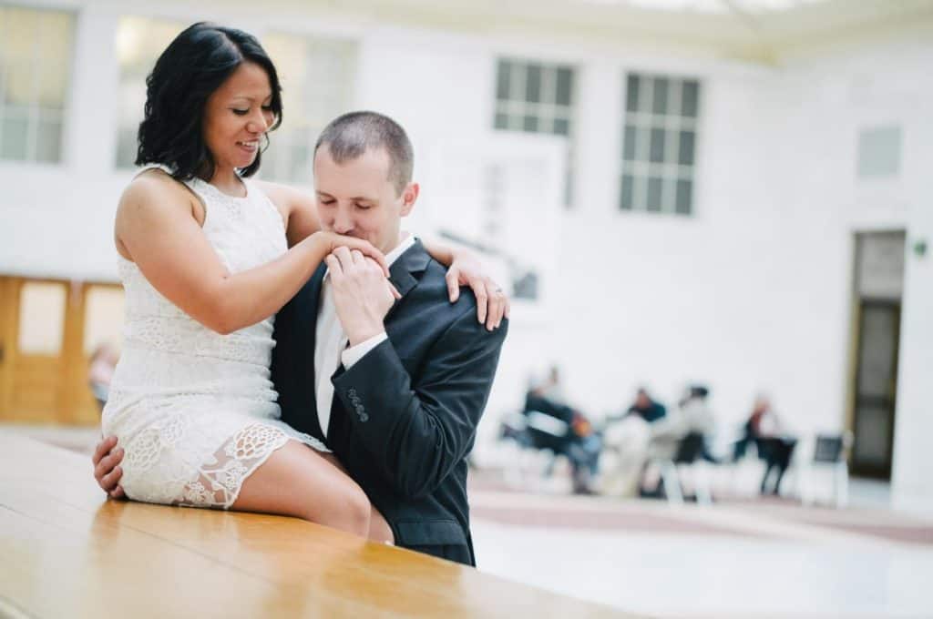 A bride and groom sitting on a bench in a large room.