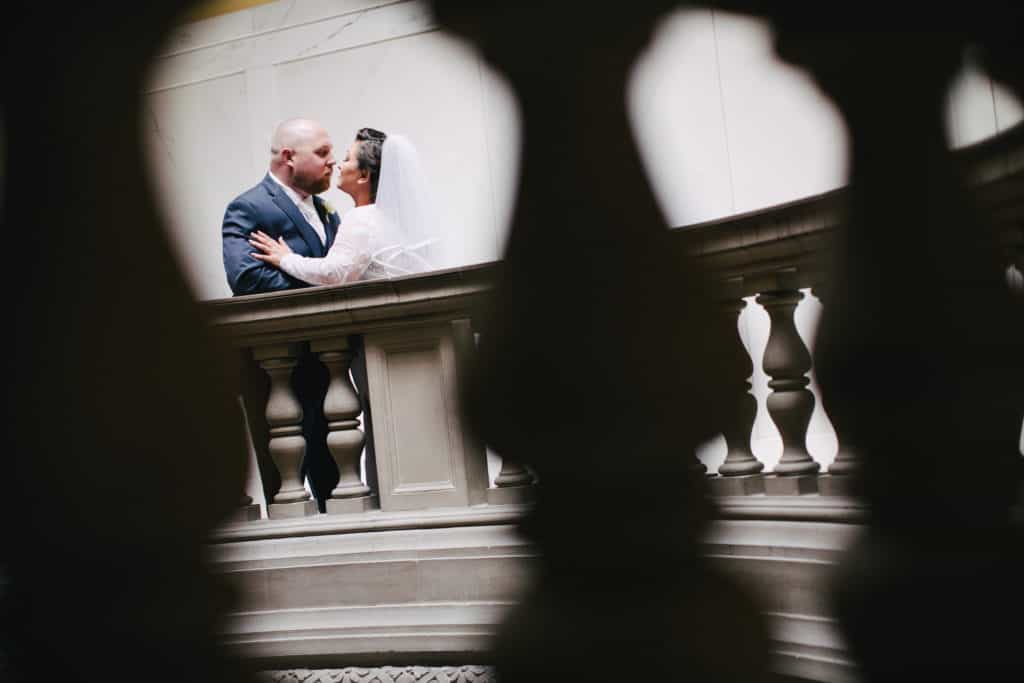 A bride and groom standing on a staircase.