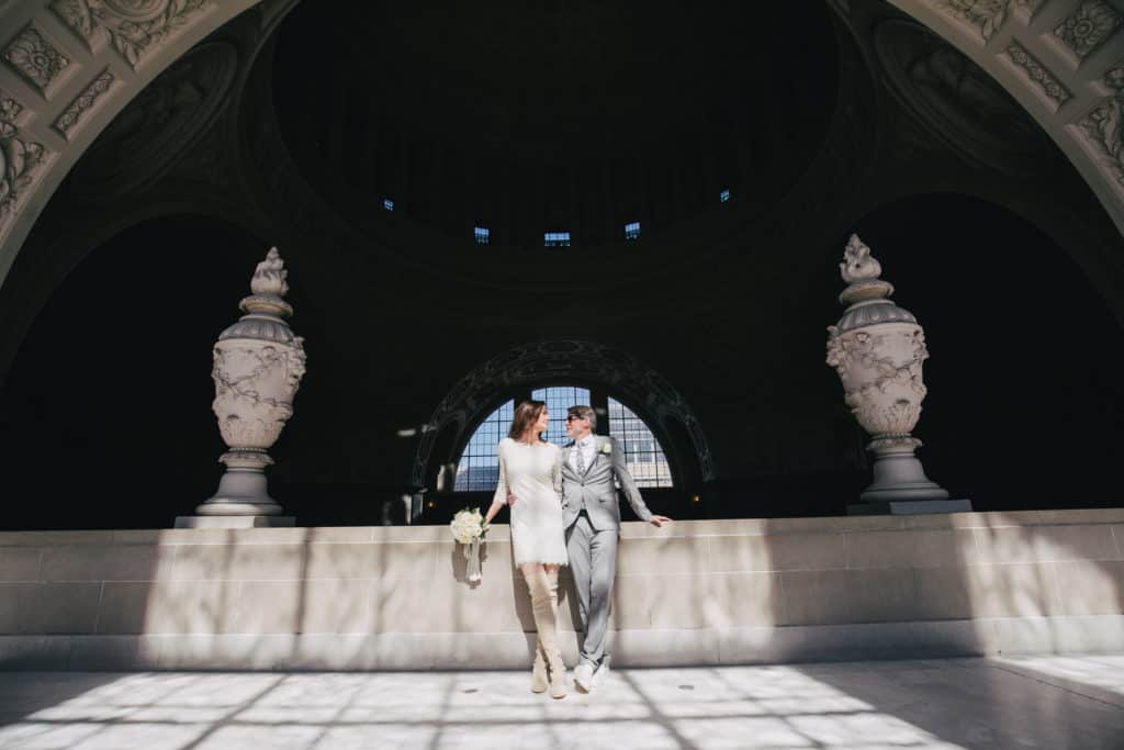 A bride and groom posing in front of an ornate building.
