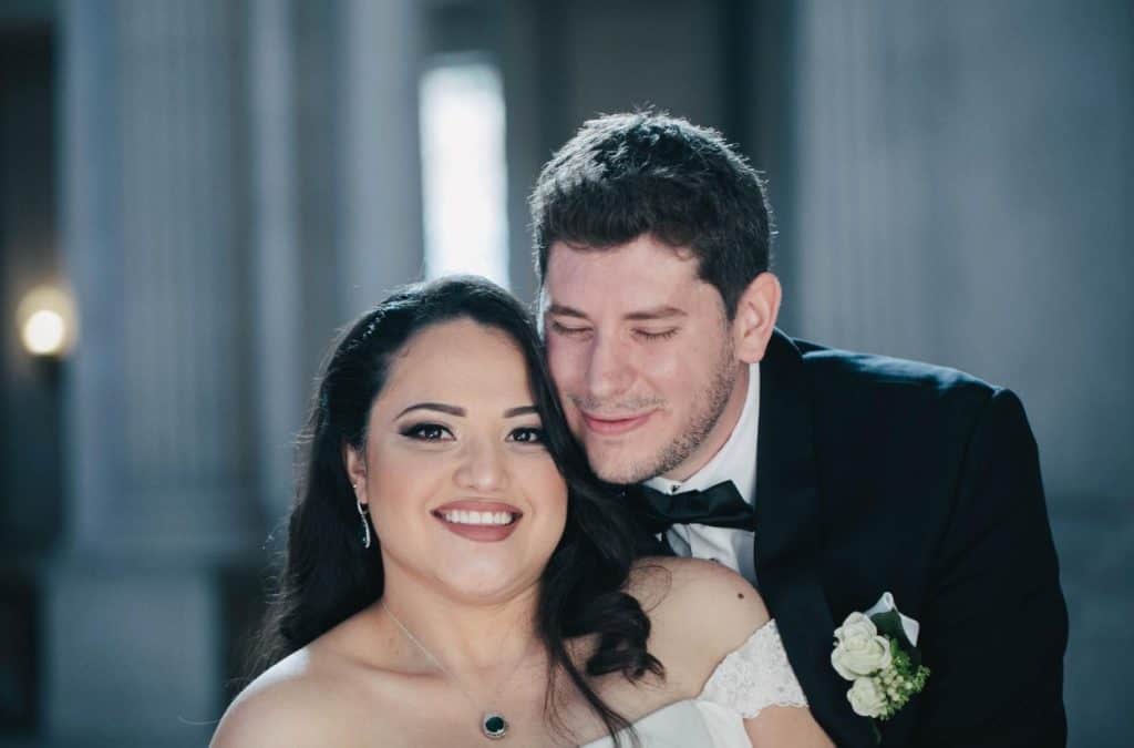 A bride and groom are posing for a wedding photo.