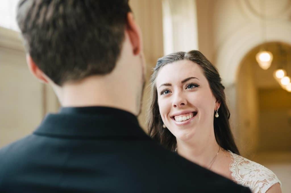 A bride and groom looking at each other in an ornate building.