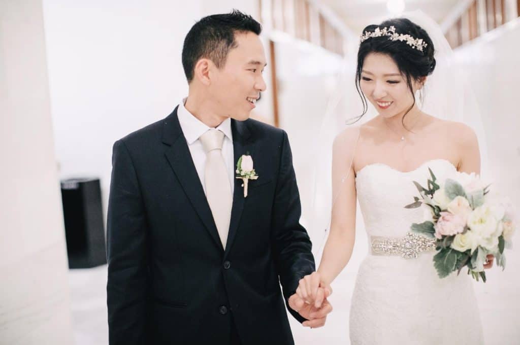 A bride and groom holding hands in a hallway.