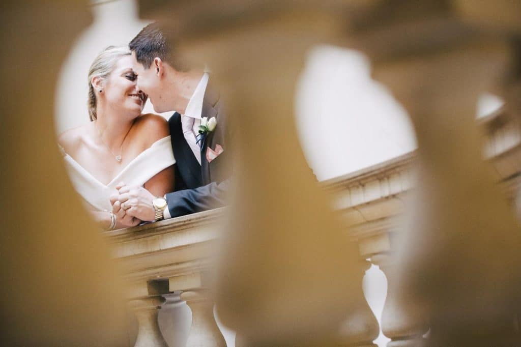 A bride and groom kissing on a staircase.