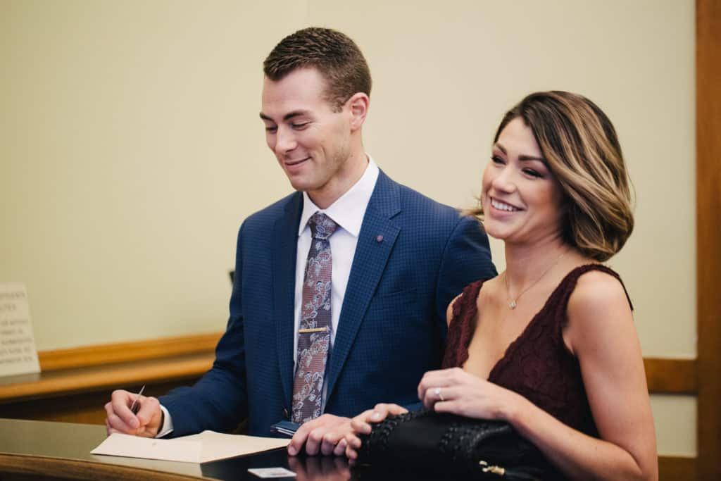 A man and woman signing a document in a courtroom.