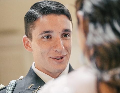 A man in a military uniform is looking at his bride.