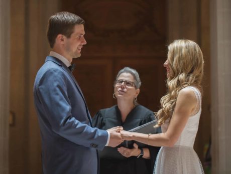 A bride and groom exchange vows in front of a judge.