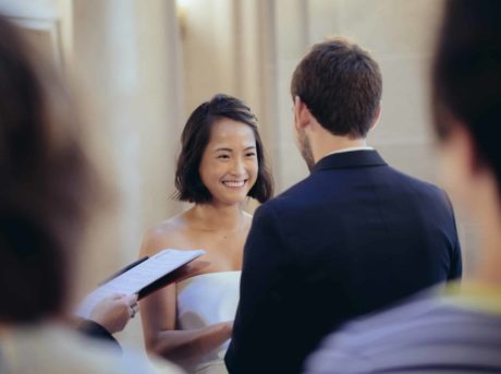 A bride and groom smiling at each other during their wedding ceremony.