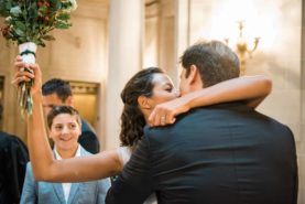 A bride and groom hugging in front of a crowd of people.