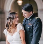 A bride and groom in a military uniform pose for a photo.
