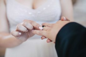 A man is putting a wedding ring on a woman's hand.